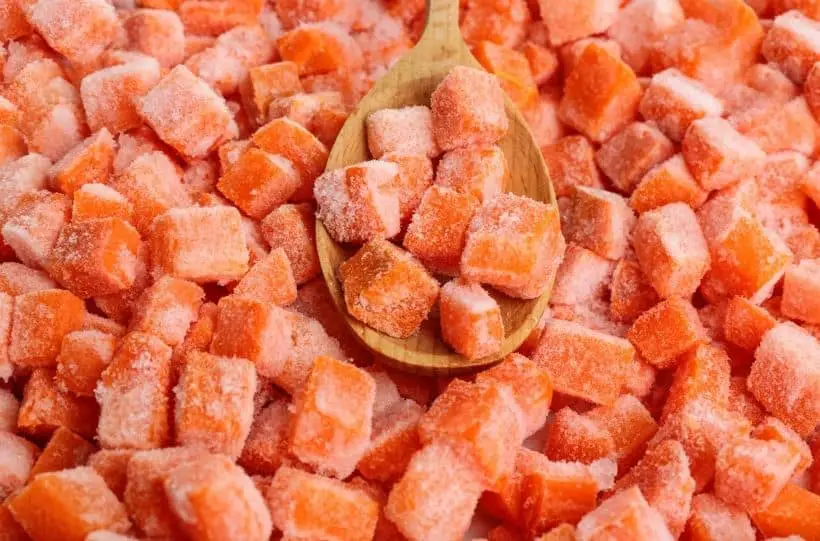 Frozen carrots with a wooden spoon